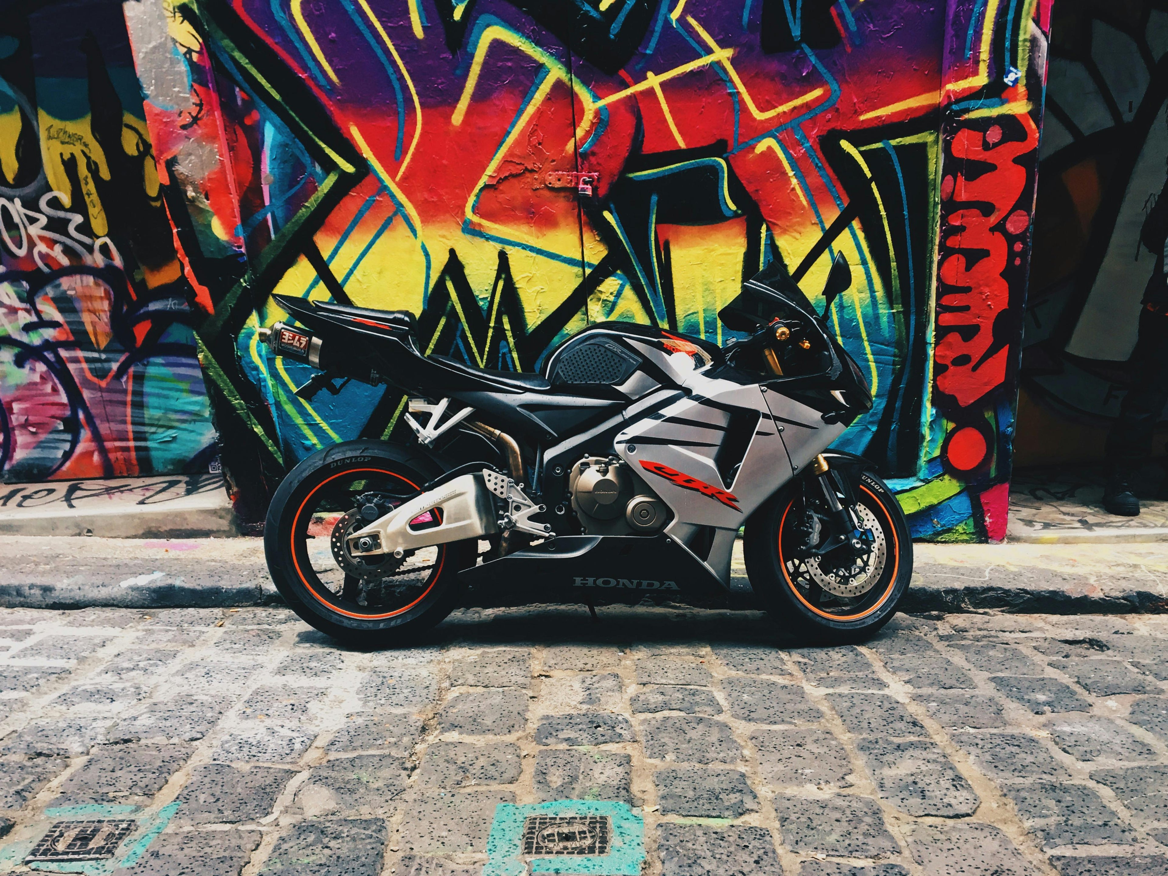 Motorcycle parked on a cobblestone street with colorful graffiti in the background